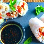Teriyaki Chicken Summer Rolls with carrots, basil, red pepper and rice noodles inside, cut in half and stacked on slate platter with Garlic Honey Soy Dipping Sauce. Easy, fun, and delicious!