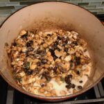 Flour, milk, broth added to beans, cajun seasoning, cauliflower and mushrooms in a pot for Creamy Cajun Cauliflower and Beans.