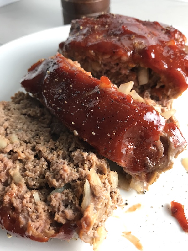 Close up picture of sliced meatloaf with ketchup on top. This 5-Ingredient Easy Meatloaf recipe may be short on ingredients, but it is loaded with flavor. The lack of breadcrumbs means you don't have them soaking up the juices, so the meat stays moist - and it's gluten free too! Parmesan cheese, onion, egg, ketchup, salt, and pepper are all that go into this yummy loaf of goodness!