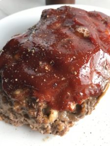 Close up picture of whole meatloaf with ketchup on top. This 5-Ingredient Easy Meatloaf recipe may be short on ingredients, but it is loaded with flavor. The lack of breadcrumbs means you don't have them soaking up the juices, so the meat stays moist - and it's gluten free too! Parmesan cheese, onion, egg, ketchup, salt, and pepper are all that go into this yummy loaf of goodness!