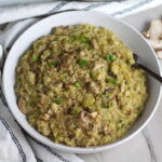 Creamy Parmesan Mushroom Quinoa Risotto in a bowl with fork. This recipe has the traditional garlic flavor in the background and the nuttiness from the  Parmesan combined with the meaty earthy flavor of the mushrooms.  There is no wine.