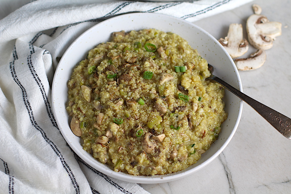 Creamy Parmesan Mushroom Quinoa Risotto in a bowl with fork. This recipe has the traditional garlic flavor in the background and the nuttiness from the  Parmesan combined with the meaty earthy flavor of the mushrooms.  There is no wine.