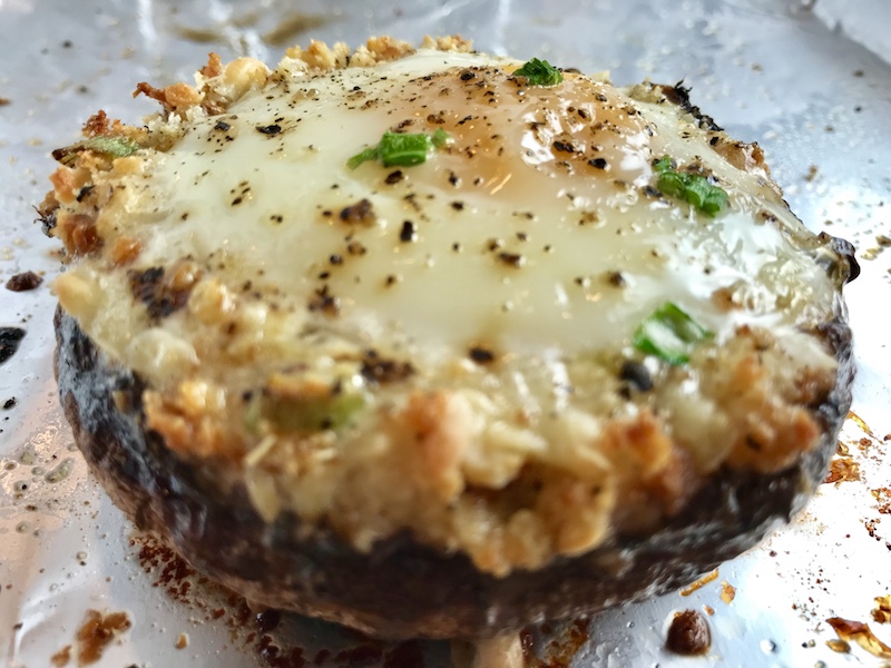 Portabella Mushroom Egg Nests on pan. Portabella mushrooms are filled with garlic, scallion, breadcrumb & Manchego cheese stuffing!  Then an egg is baked nestled in the center of all of this goodness.