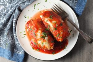 Stuffed Cabbage Rolls on a plate. They're a great make-ahead family dish! This recipe uses ground chicken, paprika, parmesan, tomato paste, garlic, and onion for tons of flavor!