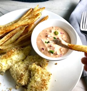 Remoulade sauce in bowl on plate with fish and chips