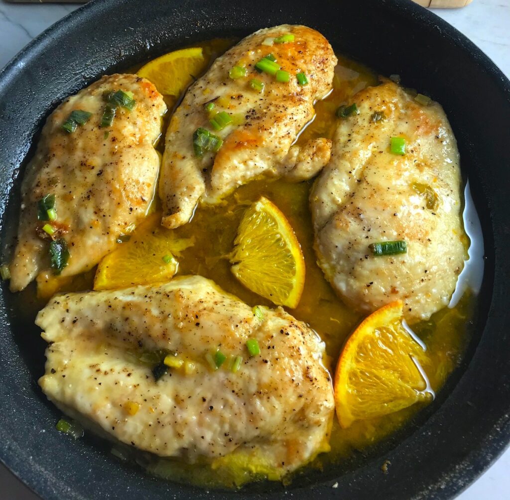 Close up of Orange Brown Butter Sauce chicken cooked in pan with orange slices.