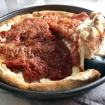 Spatula lifting slice Chicago Style pizza with tomatoes on top.This Chicago Style Pizza is a lighter and healthier version, but still AMAZING! It still has all of the gooey mozzarella cheese, but uses homemade turkey Italian Sausage, that's so delicious!