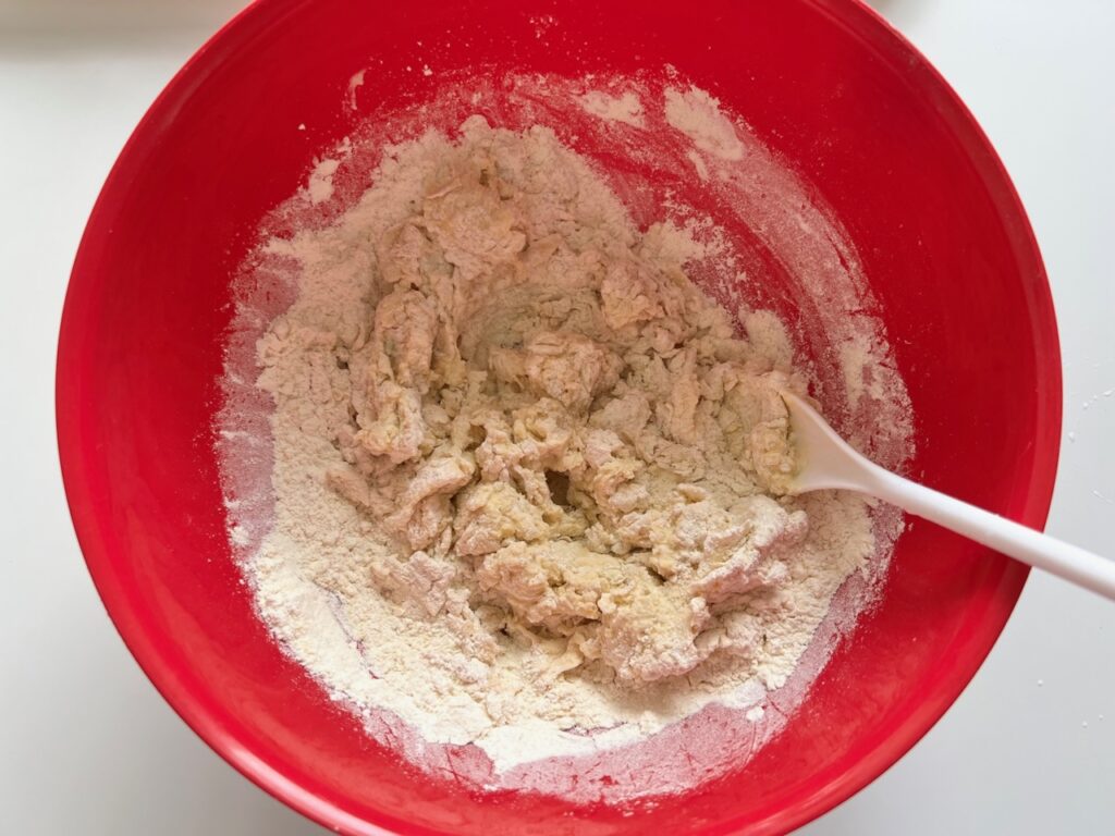 Dry and wet ingredients being stirred together in a large bowl for Chicago Pizza with Chicken Sausage.