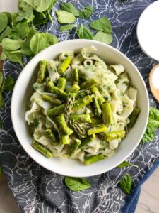 Pasta with spinach, asparagus, cauliflower sauce in bowl on blue towel