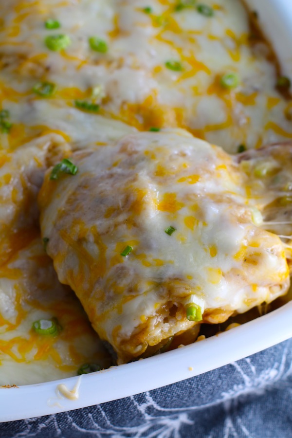 White Enchilada Casserole with Chicken & Veggies is hearty, cheesy, delicious, & easy because everything is layered in one dish. #healthydinner #familydinners #chickendinners #chickenrecipes