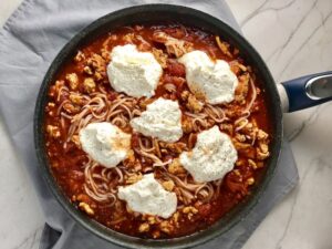This Skillet Ground Chicken Tomato Sauce with Ricotta is a delicious and simple one pan meal.  Ground chicken is seared until it gets a super browned, flavorful crust.  Then garlic, vegetable broth and tomatoes are added and cooked down into a delightful sauce that really lets the tomato shine with a meaty bite from the chicken.  After pasta is mixed in, creamy Ricotta Cheese is dolloped on and fresh basil added to garnish.  It's perfection! Bellissimo!