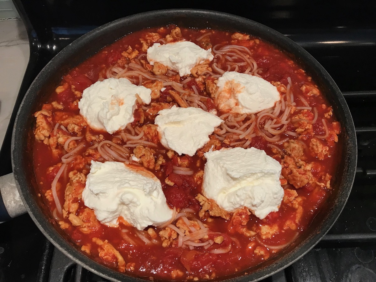 Five ricotta dollops added to ground chicken tomato sauce in a frying pan for the Tomato Chicken Ricotta Pasta recipe.