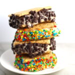 Banana Ice Cream sandwiches with graham crackers, sprinkles, and chocolate chips stacked on plate on counter. Banana Ice Cream is literally just 2 ingredients, Frozen Bananas and Almond Milk.  Add in crunchy Graham Crackers as the 3rd ingredient and you have a delicious healthy Banana Ice Cream Sandwich!  If you have never tried banana ice cream, you are in for a treat!  It tastes just like soft serve ice cream.