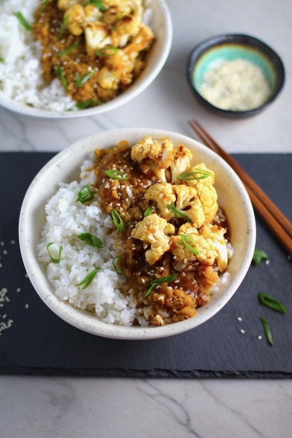 This Korean Rice Bowl on counter with Rice, Lentils and Cauliflower. This recipe is da bomb, exploding with flavor! The rice soaks up the sauce, which gives you a nutty, salty flavor from sesame oil and soy sauce, a warm and zesty kick from ginger and garlic, and sweetness from honey to balance it all out. Lentils and cauliflower give a meaty bite.