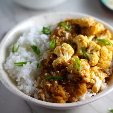 This Korean Rice Bowl on counter with Rice, Lentils and Cauliflower. This recipe is da bomb, exploding with flavor! The rice soaks up the sauce, which gives you a nutty, salty flavor from sesame oil and soy sauce, a warm and zesty kick from ginger and garlic, and sweetness from honey to balance it all out. Lentils and cauliflower give a meaty bite.