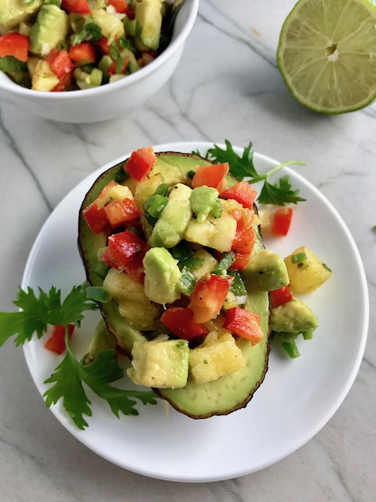 Pineapple Salsa with red pepper, jalapeño, cilantro, scallion, lime, and avocado all in half of a avocado.