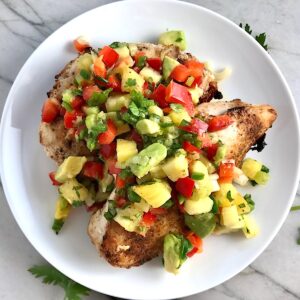 Pineapple Salsa with red pepper, jalapeño, cilantro, scallion, lime, and avocado all over grilled chicken breasts.