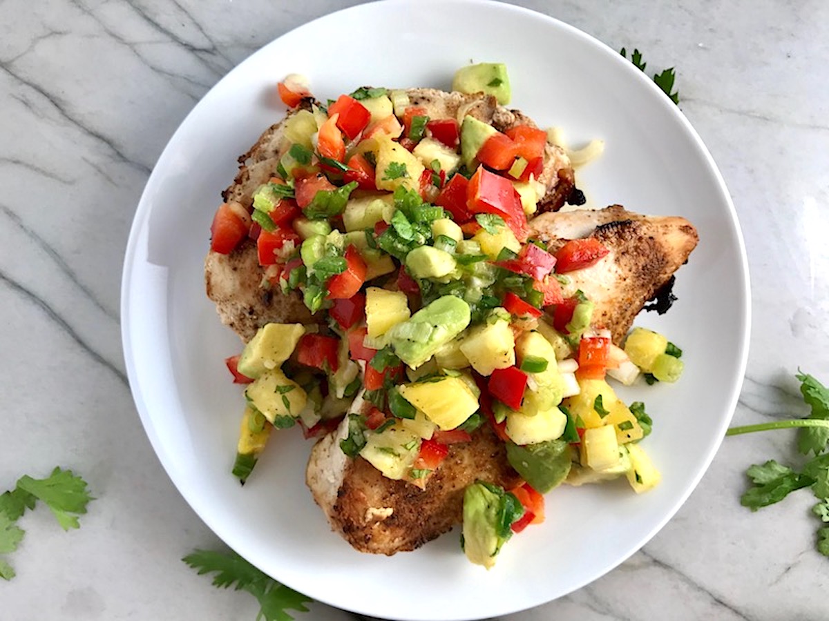 Pineapple Salsa with red pepper, jalapeño, cilantro, scallion, lime, and avocado all over grilled chicken breasts.