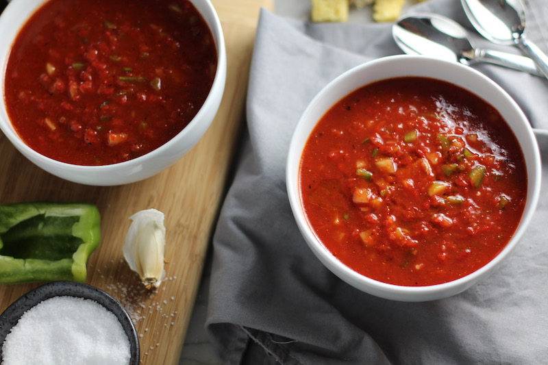 This Roast Red Pepper Gazpacho recipe is Summer in a bowl. It's cool, tangy, crunchy, fresh, and creamy. The base is tomato, but this Gazpacho recipe puts Roast Red Pepper in the starring role, which brings another layer of creamy sweetness. Then you get the crunch from the green pepper, cucumber, garlic and scallions.