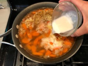 Cornstarch slurry being poured over broth with carrots and onions. Smothered Pork Chop Casserole is a true midwestern comfort dish with layers of vegetables and meaty pork chops smothered in a creamy sauce and cheese.  The pork chops in this delicious casserole are left whole so that you get an entire portion dripping in goodness in one scoop.
