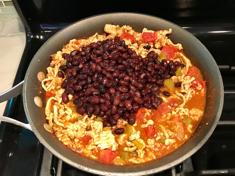 Meat, tomatoes, black beans in skillet. This Taco Casserole has corn tortillas layered with browned ground chicken seasoned with smokey mexican spices, black beans, tomatoes, and cheese, and then more cheese.