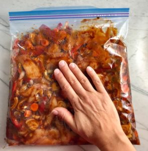 Pressing the Hoisin Chicken ingredients in the freezer bag flat with hand. This Freezer Hoisin Chicken with Red Peppers, Carrots, Onions, Ginger, and Soy sauce is delicious and so easy to make. You get sweet and savory all in one dish and it's perfect for kids because it's sweet, not spicy at all. Just freeze ahead, thaw, then cook on a sheet pan!