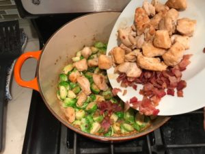 Adding cooked chicken and bacon to pot for the Easy Bacon Brussel Sprouts and Chicken recipe. It's a perfect quick Fall Recipe!  It has a creamy sauce filled with salty bacon, earthy and almost nutty seared brussel sprouts, and hearty healthy chicken. Serve over rice (or Quinoa or pasta!).