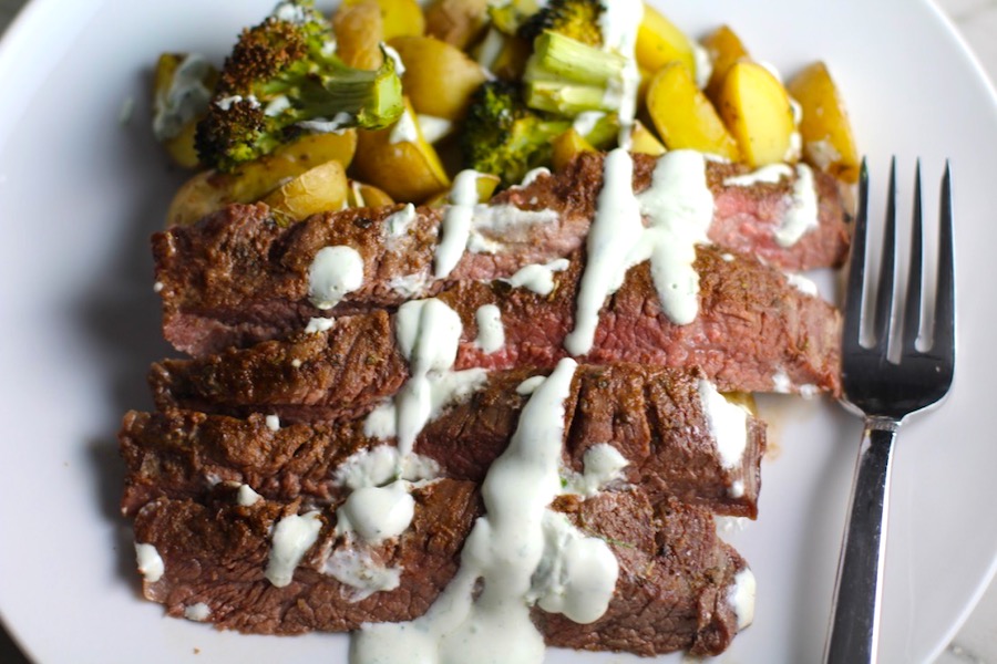 Flank Steak sliced with Potatoes & Broccoli on plate with crema drizzled on top. This is an easy and delicious Sheet Pan Dinner.  The homemade steak rub adds such wonderful flavor. To top this sheet pan dinner, you get this tangy, light Garlic Chive Crema!  Best of all, you only need 1 pan so it's a super easy clean up.  Easy and Delicious!