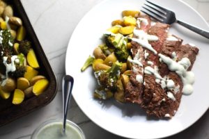 Flank Steak sliced with Potatoes & Broccoli on plate with crema drizzled on top. This is an easy and delicious Sheet Pan Dinner.  The homemade steak rub adds such wonderful flavor. To top this sheet pan dinner, you get this tangy, light Garlic Chive Crema!  Best of all, you only need 1 pan so it's a super easy clean up.  Easy and Delicious!