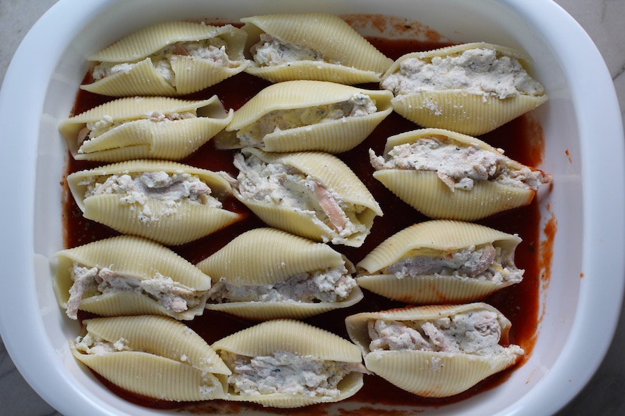 Stuffed Pasta Shells layered into a tomato sauce in a casserole dish for Turkey Ricotta Stuffed Shells in Tomato Sauce. These are the perfect way to repurpose and transform leftover Turkey or Chicken. The Shredded Turkey, Italian seasonings, mozzarella, and ricotta are stuffed in shells and topped with a simple tomato sauce and more melty mozzarella and nutty parmesan, it's a perfect dish that the family will love!