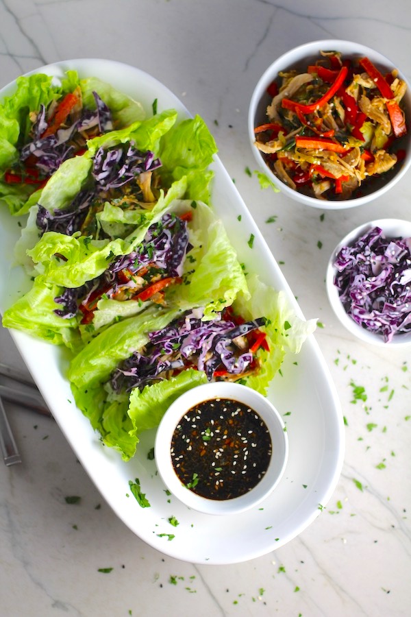Asian Lettuce Wraps on a plate with sauce. They are a fantastic way to use leftover Turkey or Chicken transforming it with new delicious flavors and textures. The turkey is stir fried with carrots, red pepper, and brussel sprouts in a flavorful ginger, garlic, & sesame sauce. It's layered in lettuce wraps with rice and a cool, crunchy purple cabbage sesame slaw. Serve with a Garlic Honey Soy Sauce....YUM!!!