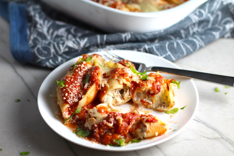Turkey Ricotta Stuffed Shells in Tomato Sauce on plate cut with casserole dish in background. These are the perfect way to repurpose and transform leftover Turkey or Chicken. The Shredded Turkey, Italian seasonings, mozzarella, and ricotta are stuffed in shells and topped with a simple tomato sauce and more melty mozzarella and nutty parmesan, it's a perfect dish that the family will love!