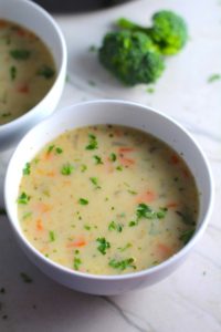 Slow Cooker Creamy Broccoli Soup in a bowl with second bowl in back. This is easy, comforting, and delicious! With Carrots, Broccoli, Onion, Garlic, and Oregano, this is one flavorful soup. And, there is no heavy cream, just milk and a little half and half mixed with cornstarch, so it's healthy and gluten free!