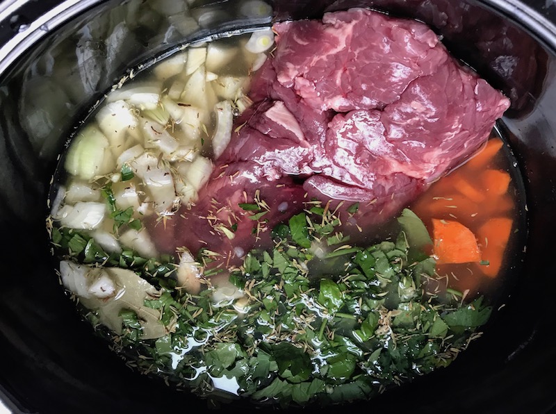 Beef, carrots, onion, broth, and other ingredients in crockpot for the Slow Cooker Beef Stew over Noodles recipe.  It's comfort food full of flavor and texture with carrots, onion, garlic, thyme, beef, and more. Now, try pouring that salty, chunky, saucy goodness over noodles...yup, even more amazing!  #beefstew #crockpot #slowcooker #easydinners #dinnerrecipes