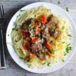 Slow Cooker Beef Stew over Noodles on a plate. This is downhome comfort food that's full of flavor and texture with carrots, onion, garlic, thyme, beef, and more. Now, try pouring that salty, chunky, saucy goodness over noodles...yup, even more amazing!#beefstew #crockpot #slowcooker #easydinners #dinnerrecipes