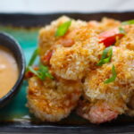 Baked Coconut Shrimp on plate with Sriracha Sauce. Crunchy and utterly irresistible, this 30-Minute Baked Coconut Shrimp recipe is one that you have got to try!  They are baked, not fried, so they are EASY to cook and HEALTHIER for you too! 