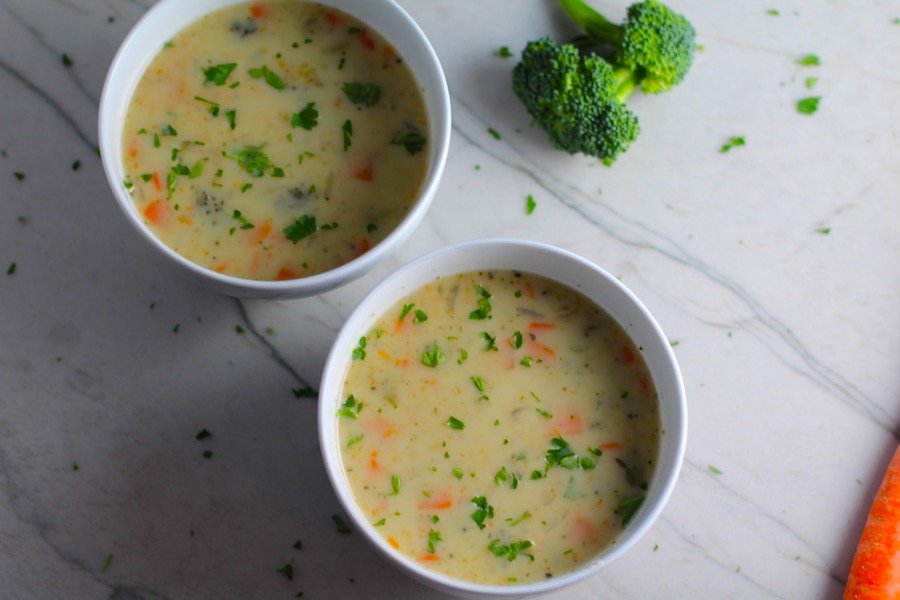 Slow Cooker Creamy Broccoli Soup in two bowls on counter with crockpot in back. This is easy, comforting, and delicious! With Carrots, Broccoli, Onion, Garlic, and Oregano, this is one flavorful soup. And, there is no heavy cream, just milk and a little half and half mixed with cornstarch, so it's healthy and gluten free!