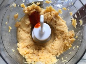 Blended Chickpeas and Sriracha in food processor for Magical Sriracha Hummus.  This recipe is seriously the easiest hummus you will ever make and it's perfect for snacking or adding to a meal.  The chickpeas have so much flavor and the Sriracha gives it a kick that is totally addictive!