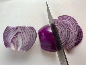 Red Onions being sliced for pickling for Slow Cooker Pork Tacos with with Pickled Onions, Shredded Cheese, and Cilantro Lime Crema drizzled on top!  It's such an easy dinner since the pork cooks in the slow cooker to be perfectly seasoned and fall apart tender. #tacos #easydinner #glutenfree #dinner #mexican #pork