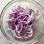 Red Onions in bowl before pickling for Slow Cooker Pork Tacos with with Pickled Onions, Shredded Cheese, and Cilantro Lime Crema drizzled on top!  It's such an easy dinner since the pork cooks in the slow cooker to be perfectly seasoned and fall apart tender. #tacos #easydinner #glutenfree #dinner #mexican #pork