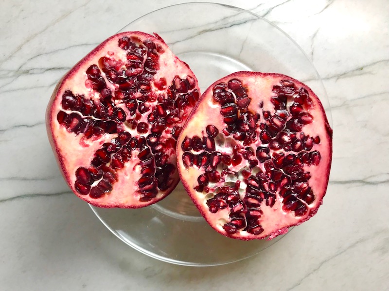Pomegranate cut in half on plate for Quinoa & Kale Salad with Roasted Chickpeas, Pomegranate, Feta, red pepper, and Creamy Lemon Dressing. #glutenfree #lunch #dinner #healthyrecipes #healthyfood #salads #quinoa #kale