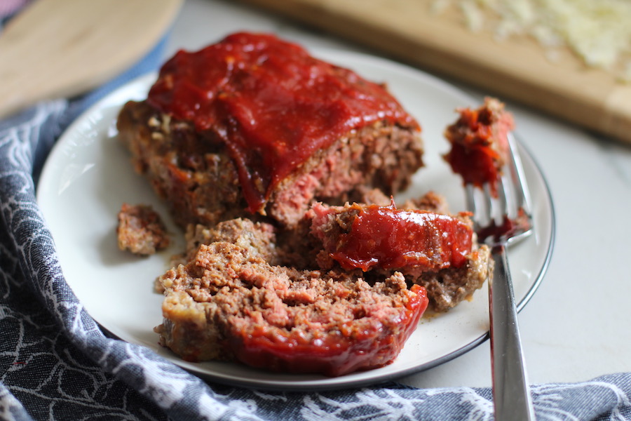 5-Ingredient Chipotle Meatloaf sliced on white plate. This recipe adds a spicy mexican flare with Chipotle Peppers in Adobo Sauce and Cheddar Cheese.  It's incredibly easy, incredibly moist, and incredibly delicious!  A family dinner favorite! #meatloaf #mexican #easydinner #familydinner #dinner #easyrecipes #beef