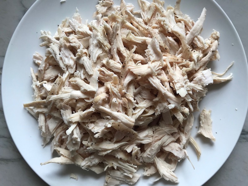 Shredded chicken on a plate for Curry Chicken Salad. It has so many fantastic flavors and textures!  The chicken breast is simply roasted and mixed with a creamy sweet and savory curry dressing.  Red pepper gives you a fresh crunch, scallion gives a savory bite, and raisins give a burst of sweet.  #chicken #chickenrecipes #chickensalad #currychicken #mealprep #lunch #healthyrecipes