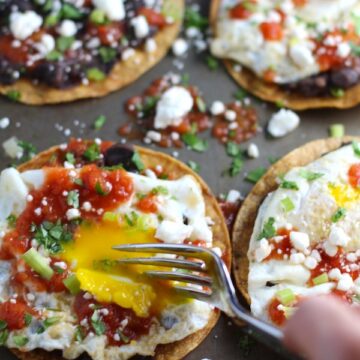 Huevos Tostadas are utterly delicious! They are similar to Huevos Rancheros but are a pick up and eat with your hands version! They have crispy corn tortillas topped with creamy mashed black beans, a salty fried egg, smoky tomato sauce, cheese, and scallions! #huevosrancheros #eggs #brunch #mexicanrecipes #vegetarian #meatlessrecipes