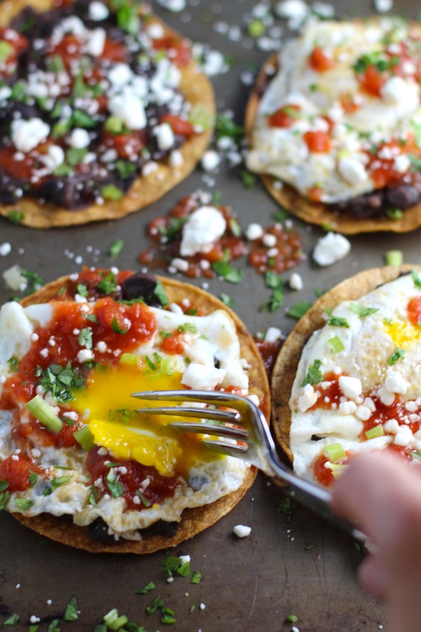 Huevos Tostadas are utterly delicious! They are similar to the better known Huevos Rancheros but are a pick up and eat with your hands version! They have crispy corn tortillas topped with creamy mashed black beans, a salty fried egg, smoky tomato sauce, cheese, and scallions! #huevosrancheros #eggs #brunch #mexicanrecipes #vegetarian #meatlessrecipes