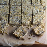 No Bake Energy Bites on parchment and cut into squares. These Easy Nut-Free, No-Bake Energy Bites with Chocolate Chips are magnificent!  They are sweet, chewy, crunchy, & healthy.  Only minutes to make & no Baking! Breakfast, snack, or dessert. #energybars #granolabars #snackrecipes #healthyfood #healthyrecipes #healthysnacks #healthybreakfast #healthydessert