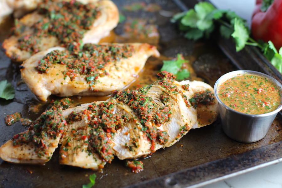 Chicken Chimichurri Rojo on a pan. It is roasted Chicken topped with a cool, fresh, tangy, and incredibly full-flavored!  The Rojo comes from the addition of red pepper.  All of the ingredients simply get blended in a food processor so it could not be easier!  #chicken #chickenrecipes #chimichurri #easychicken #easydinners #dinner
