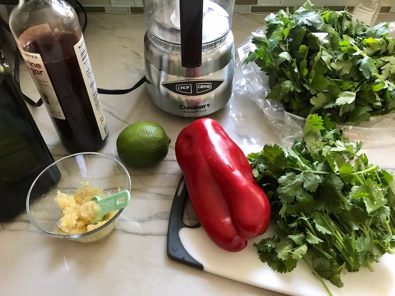Ingredients on counter for the Chicken Chimichurri Rojo. It is broiled or grilled Chicken topped with a cool, fresh, tangy, and incredibly full-flavored!  The Rojo comes from the addition of red pepper.  All of the ingredients simply get blended in a food processor so it could not be easier!  #chicken #chickenrecipes #chimichurri #easychicken #easydinners #dinner