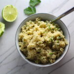 Cilantro Lime Quinoa in a bowl with spoon with lime and cilantro on counter. It's fluffy, nutty, citrusy, salty, and the perfect accompaniment for any protein or vegetable!  With just a few simple ingredients, you can make this fantastic healthier alternative to rice. #quinoa #quinoarecipes #sides #healthyfood