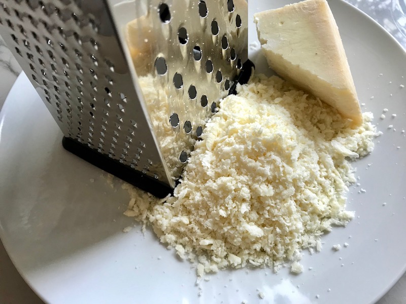 Grating Parmesan Cheese for  Artichoke Spinach Stuffed Zucchini Recipe. Each fantastic bite gives you creamy artichoke, nutty cheesy Parmesan, spinach, and zucchini. Prepare entirely ahead, then bake 20 minutes and enjoy! #vegetarian #zucchini #stuffedzuchini #spinach #artichoke #springrecipes #healthyfood #healthydinner #healthyrecipes #glutenfree